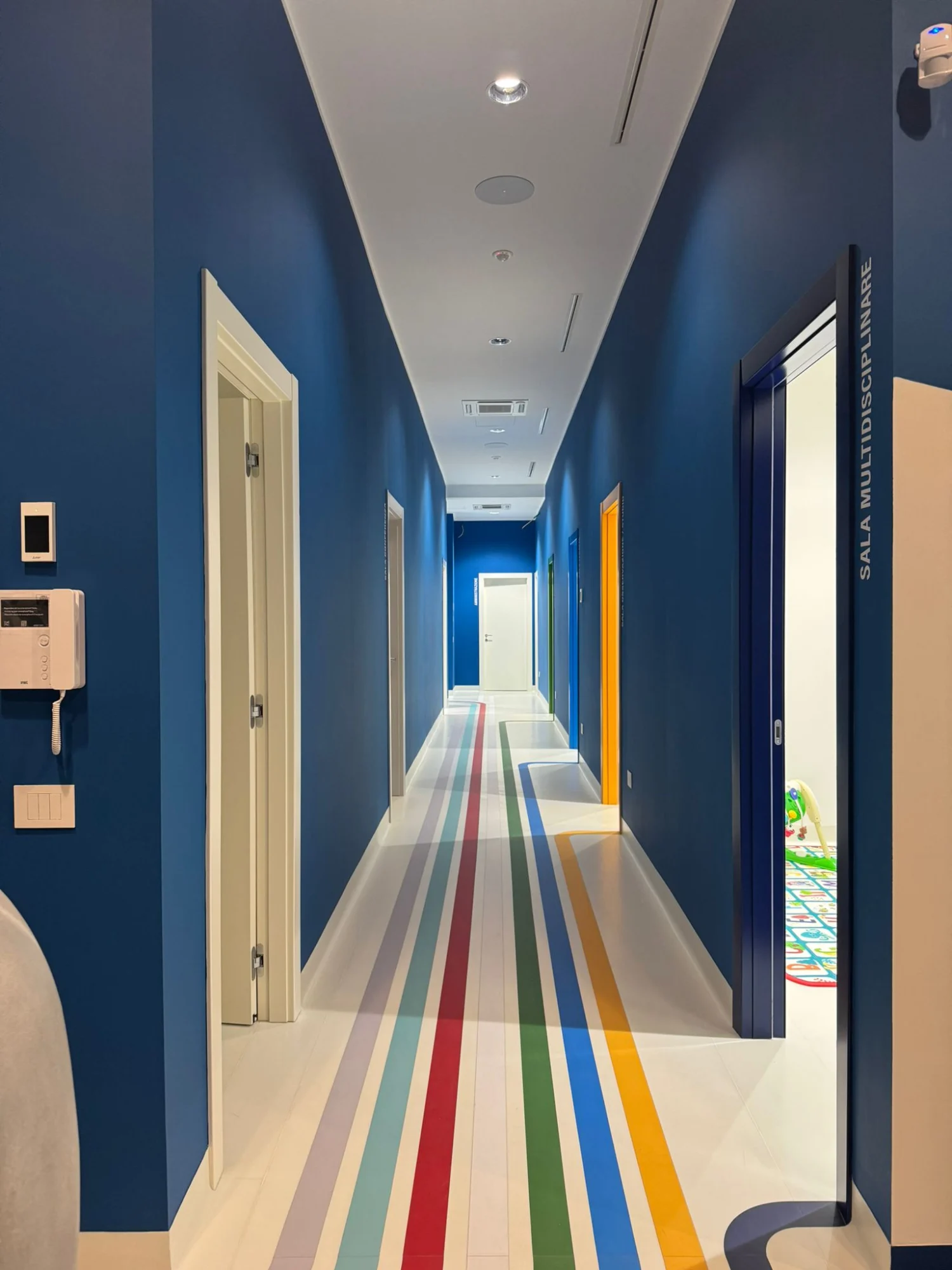 Corridoio del Centro ABA for Disability di Salerno con pareti blu e linee colorate a pavimento che guidano l’orientamento