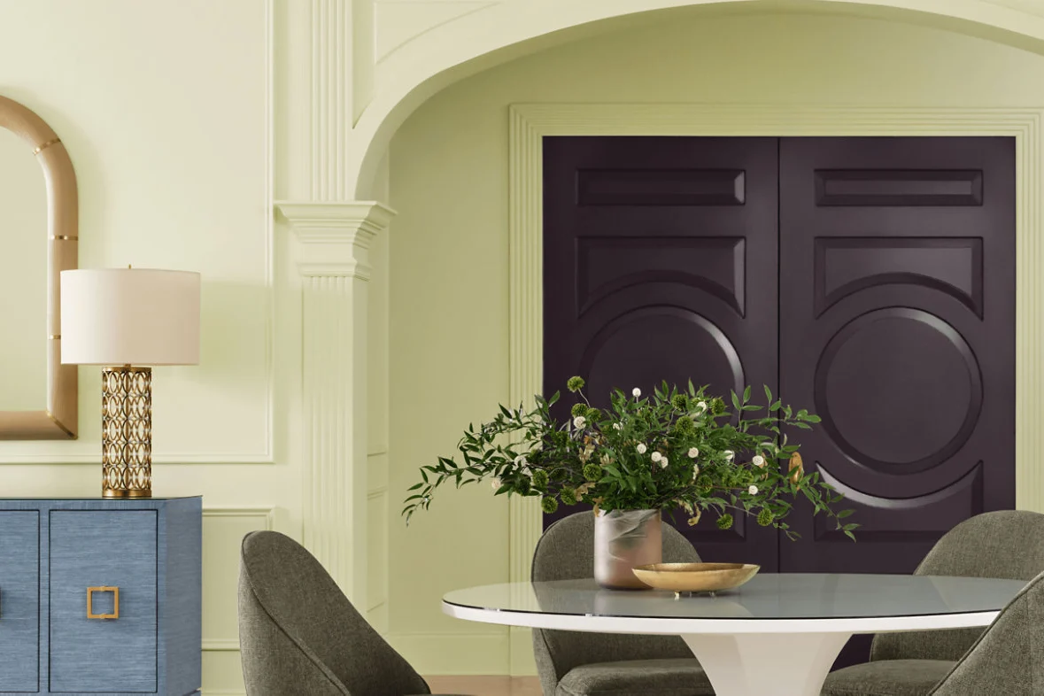 Dining room with pale herbal green walls, an archway and a plum door