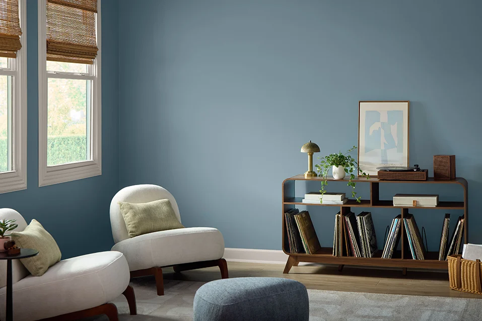 Living room with blue grey walls, white armchairs and a wooden unit