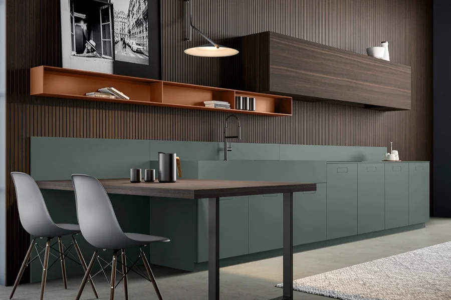 Kitchen with dark sage green base units, a copper shelf and dark wood wall unit, table and grey chairs