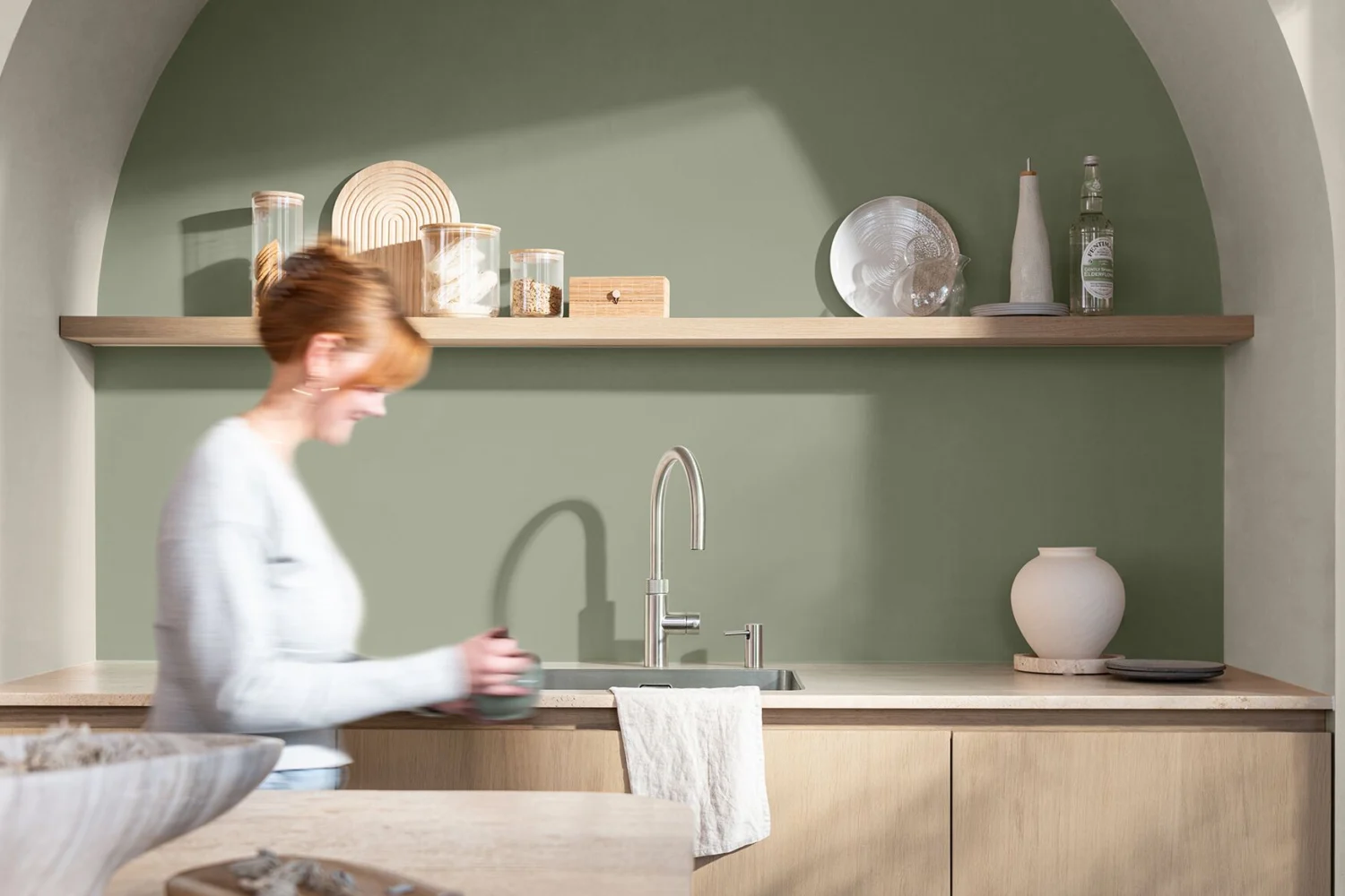 Kitchen with an arched alcove painted sage green and a wooden shelf