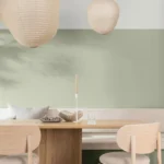 Dining room with sage green walls, pale wood table and paper pendant lamps