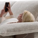 Divano David di BertO, seduta relax sul bracciolo in piuma con smartphone in carica tramite porta USB-C