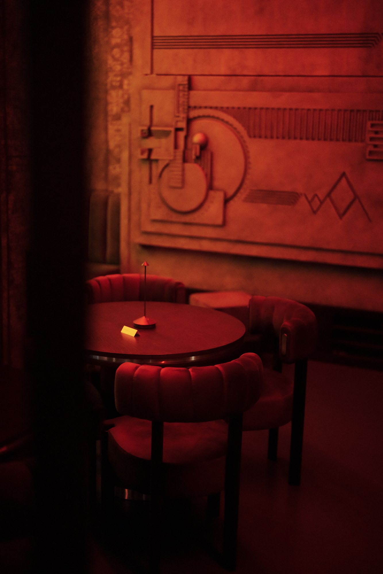 Sala lounge di Drink Kong Campo Marzio con bassorilievo ispirato alla Hollyhock House e poltroncine in velluto