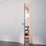 Open white Eclisse flush door set within a continuous wall