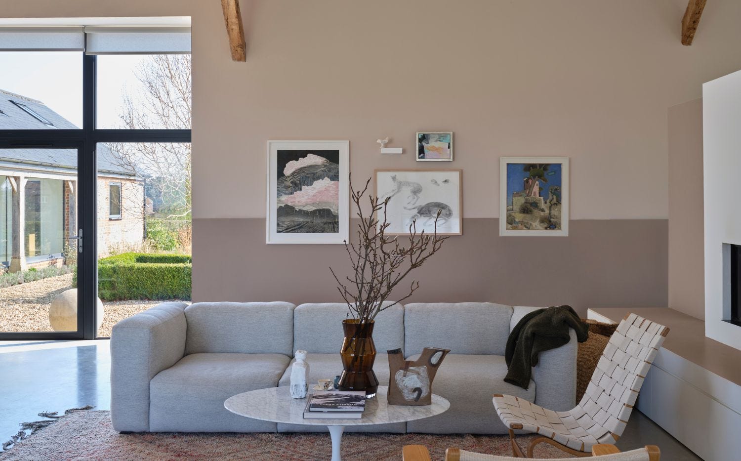 Living room with two-tone pinkish neutral walls, pale upholstery and exposed timber beams