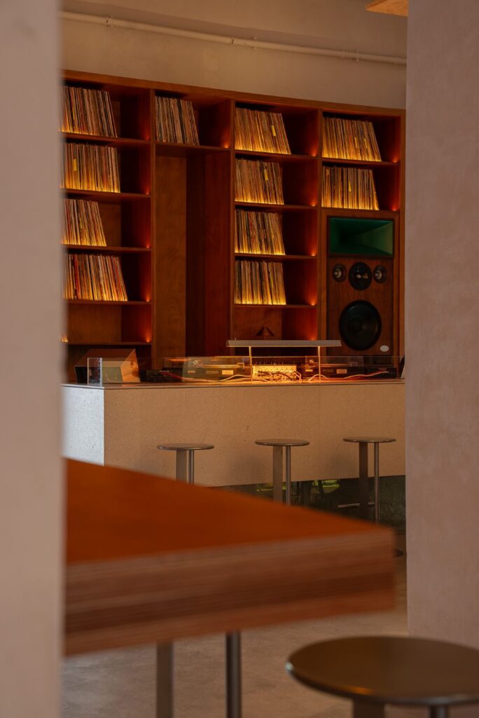 Consolle con giradischi su bancone in pietra davanti alla libreria di vinili retroilluminata di Frissón