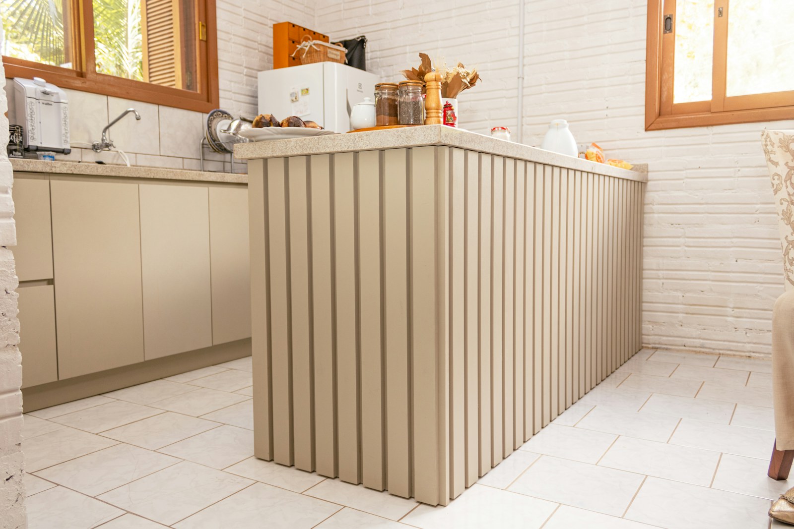 Kitchen island with sand-coloured vertical fluted cladding
