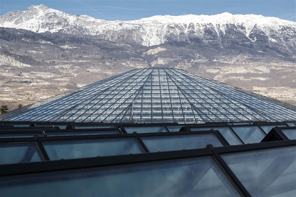 The glass and steel dome of the Mart in Rovereto, with the mountains beyond