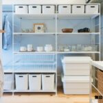Scaffali MUJI con contenitori bianchi, stoviglie e cestelli in una cucina