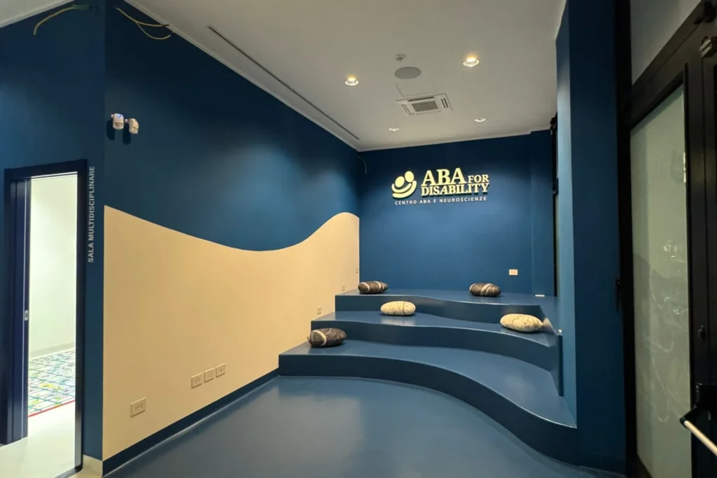 Sala del Centro ABA for Disability di Salerno con pareti blu, onda color sabbia e gradoni con sedute a forma di sasso