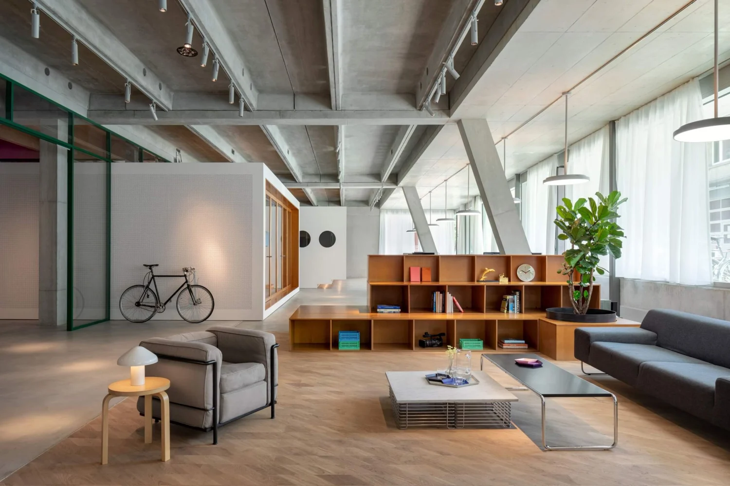 Ampio loft con soffitto in cemento e travi metalliche e parquet in rovere naturale