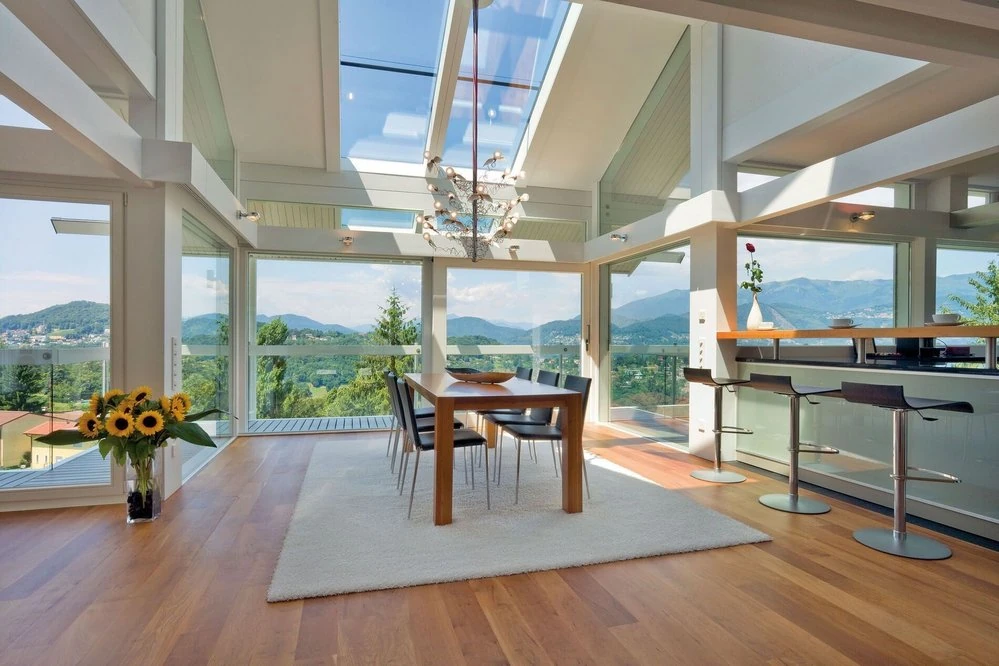 Dining area in a HUF HAUS timber-and-glass home overlooking the landscape