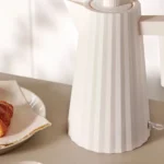 Regali di design per Natale bollitore Plissé di Alessi sulla tavola della colazione