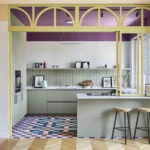 Zona giorno di Residenza B05 a Milano con vetrata ad arcate verde salvia, cucina, soffitto viola e pavimento a mosaico
