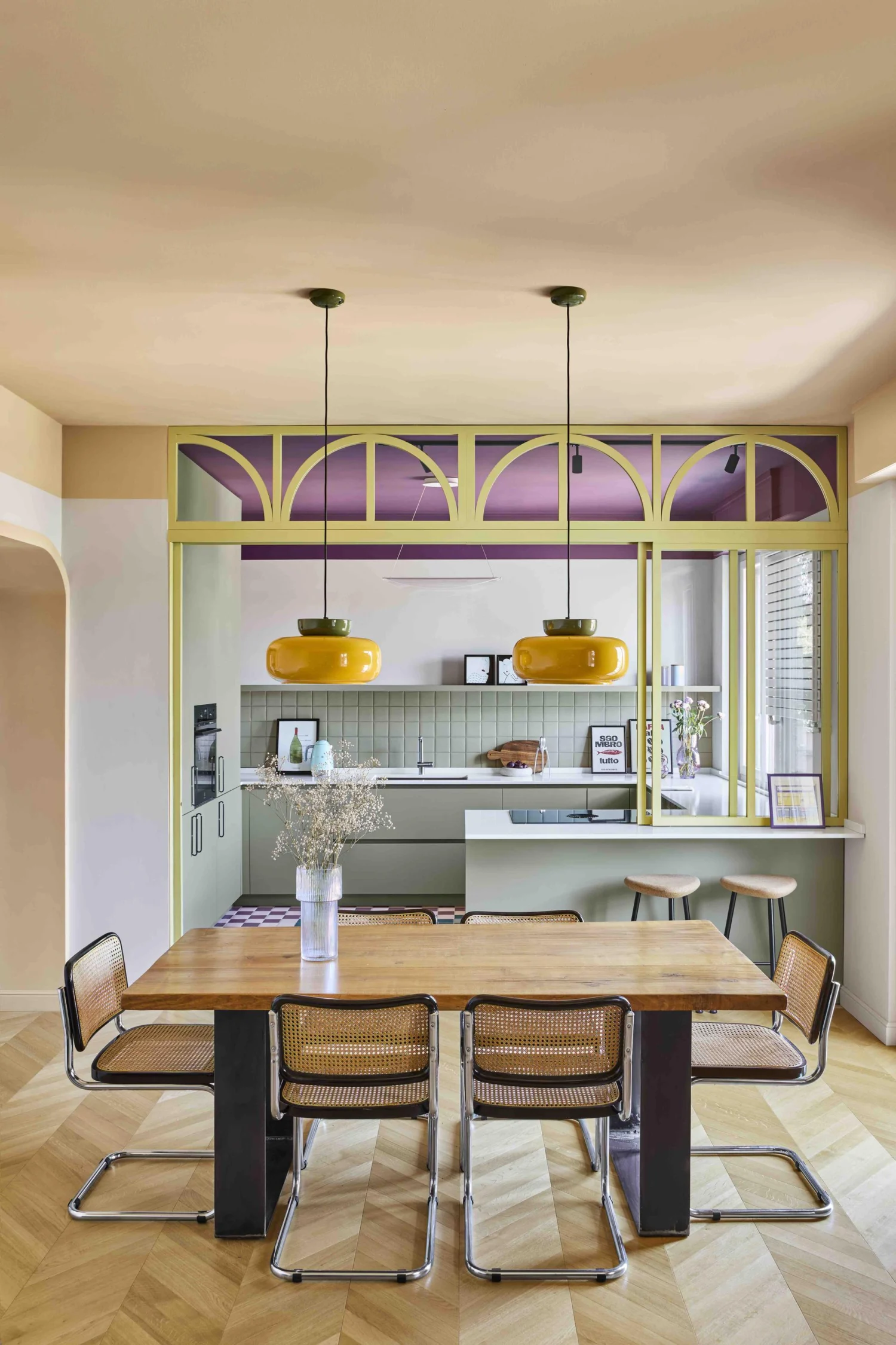 Cucina e zona pranzo di Residenza B05 con tavolo in legno, sedie a sbalzo, lampade a sospensione e vetrata ad arcate