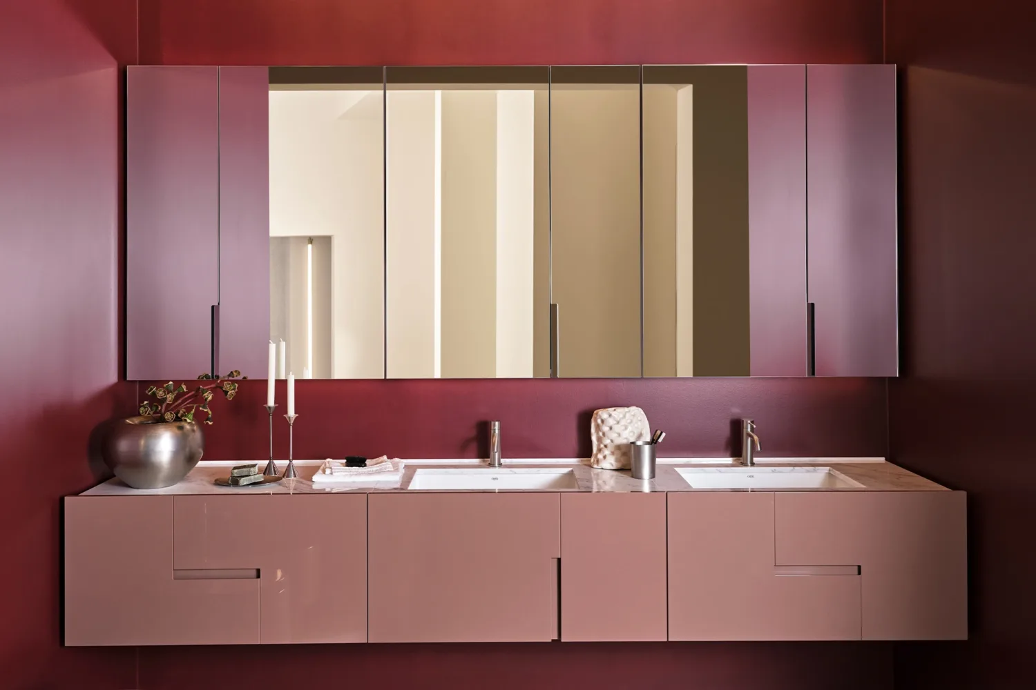 Pink wall-hung vanity with double basin and mirrored cabinets on a burgundy wall