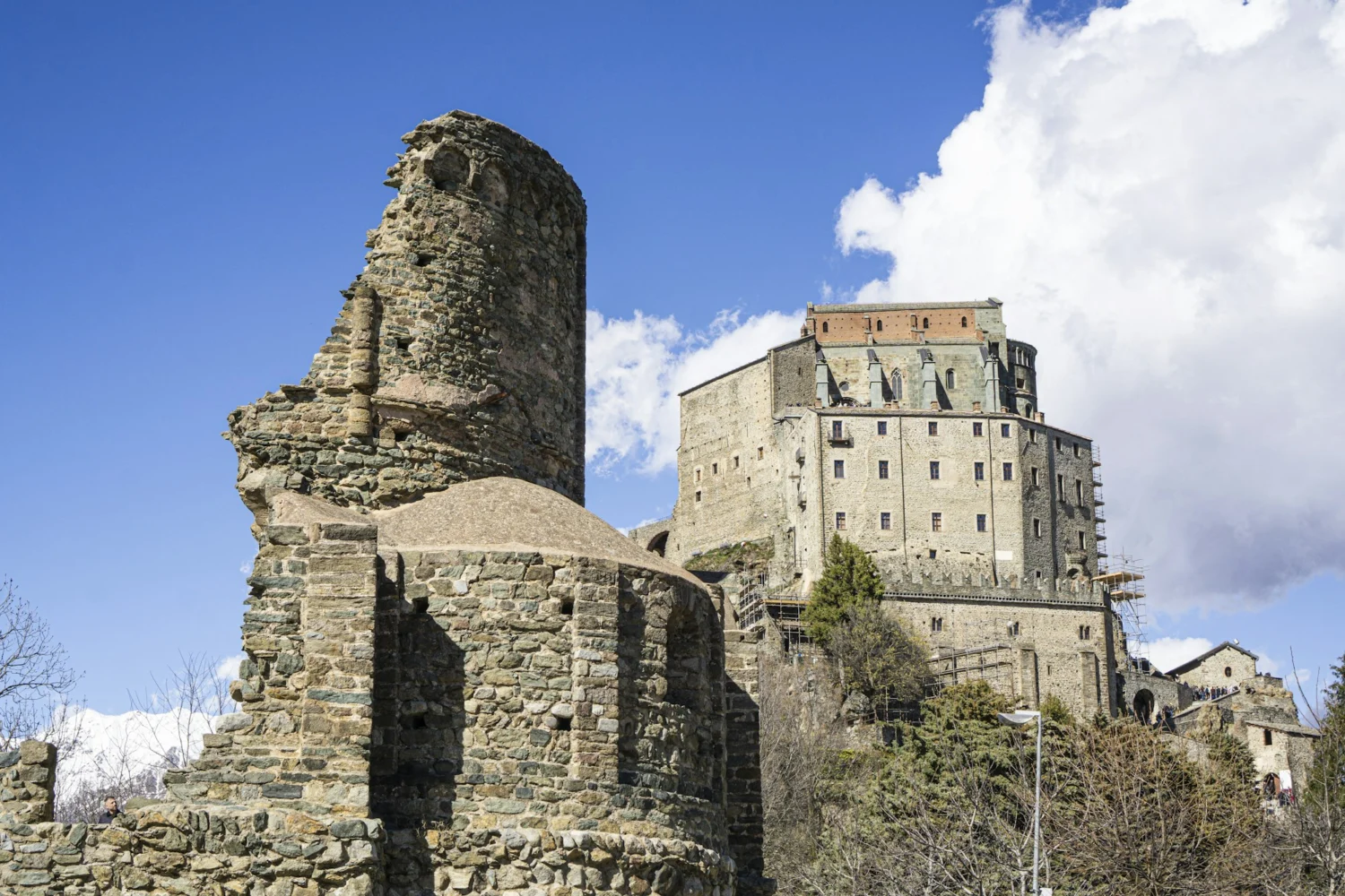 The stone ruins of the New Monastery of the Sacra di San Michele with the church in the background