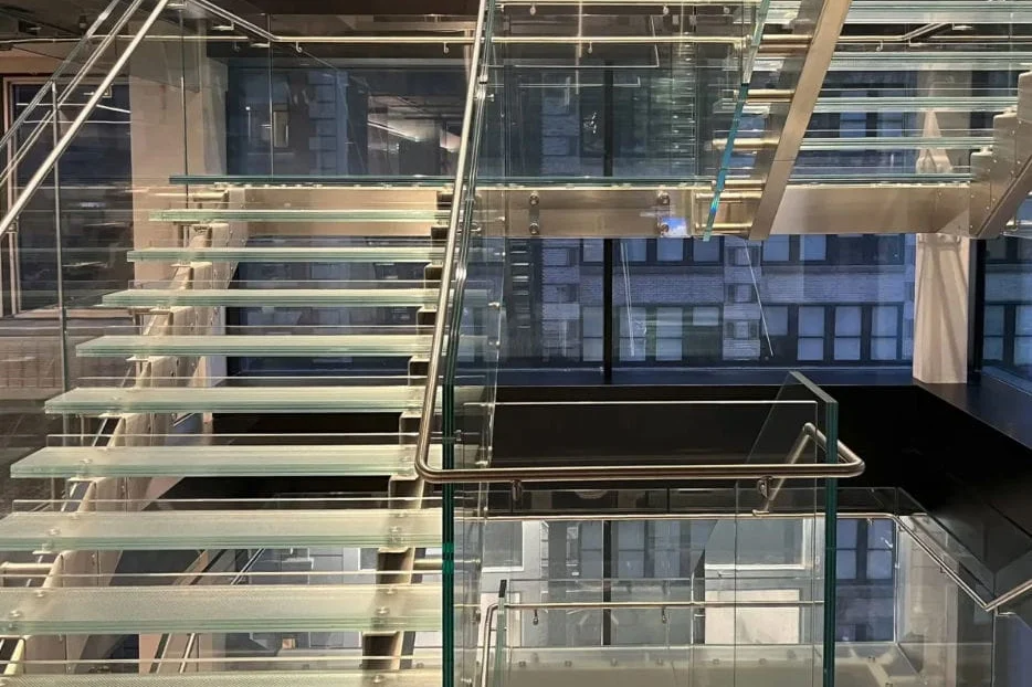 Scala interna con gradini in vetro extrachiaro e struttura in acciaio inox spazzolato