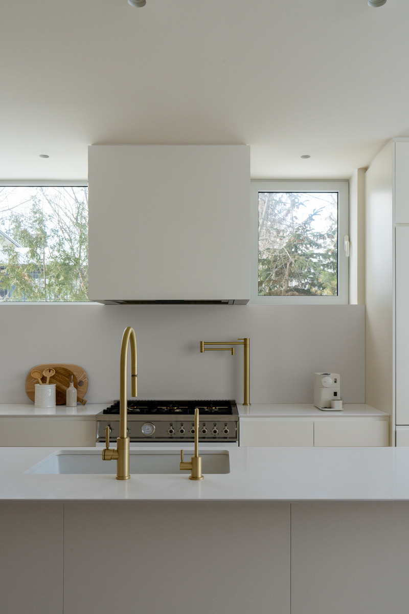 White kitchen at the MI-1 Residence with a gold-toned tap and a countertop coffee machine