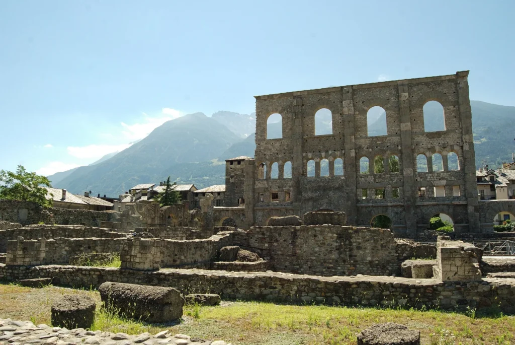 La facciata del teatro romano di Aosta con gli ordini sovrapposti di arcate e le montagne sullo sfondo
