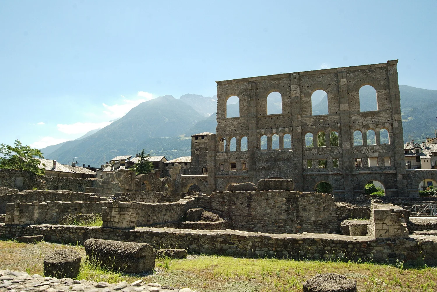 The façade of the Roman theatre in Aosta with superimposed tiers of arches and mountains behind